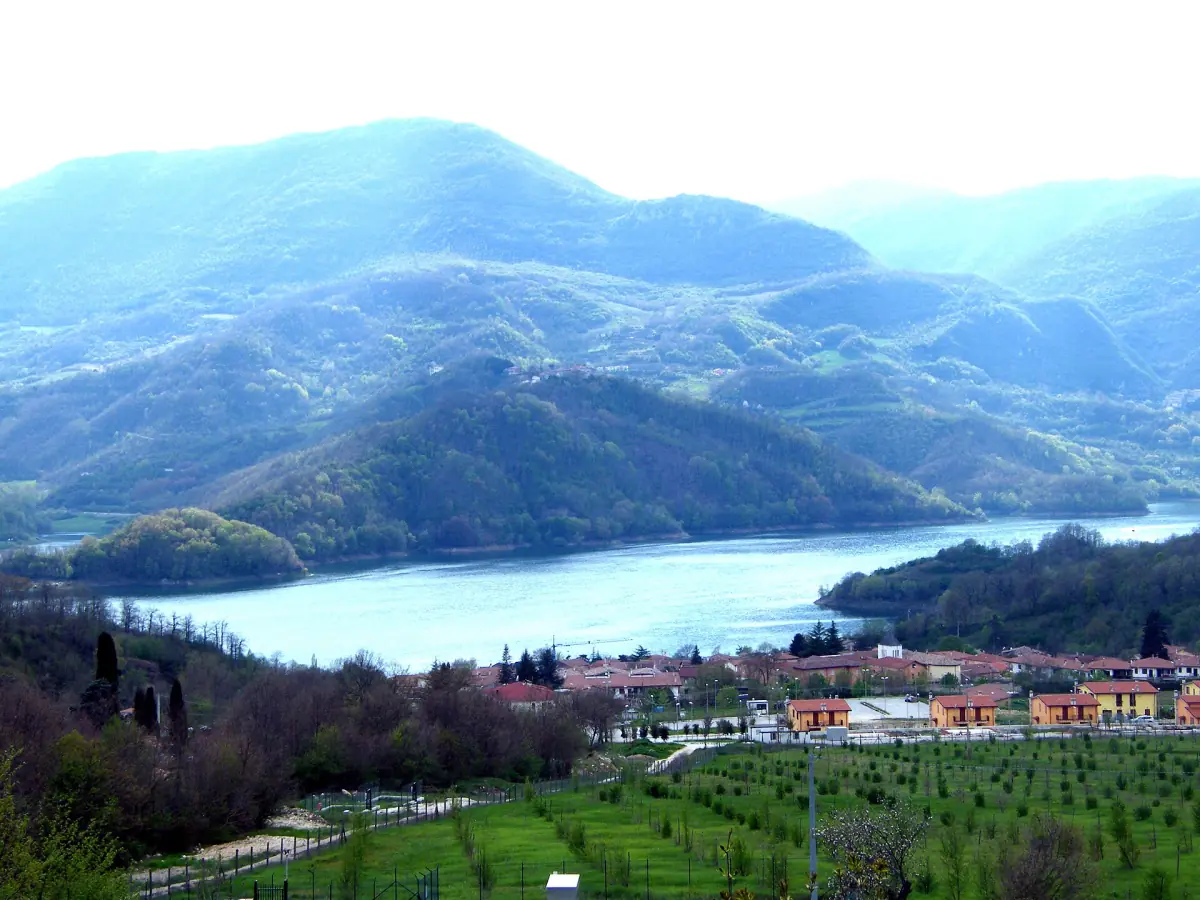 Borgo San Pietro sulla riva del Lago del Salto con le montagne dietro