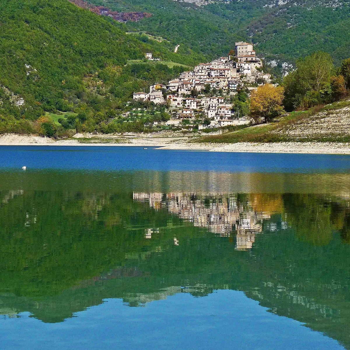 Castel di Tora in cima al colle riflesso nell'acqua verde del lago