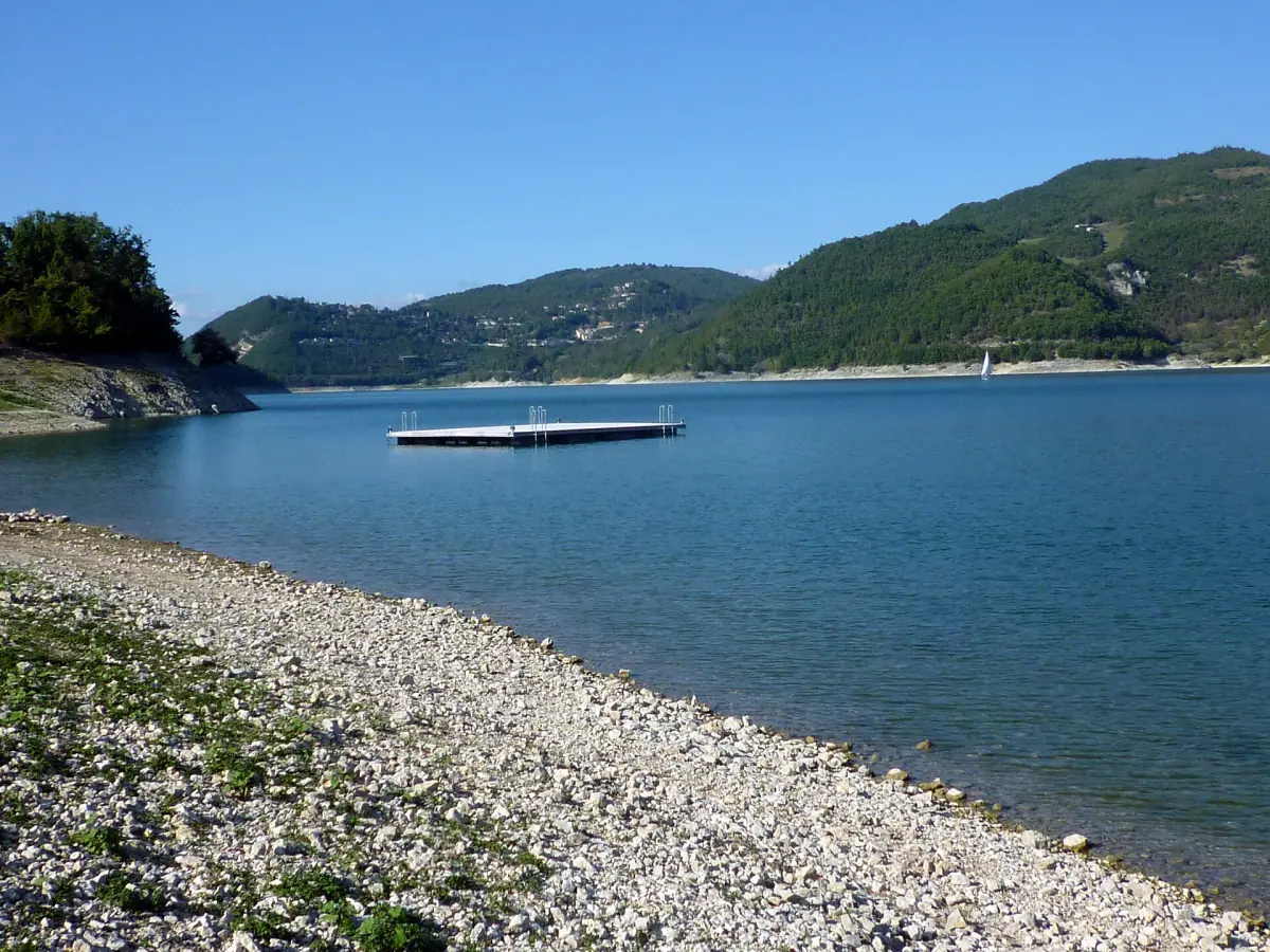 Riva di ciottoli del Lago del Turano con una piattaforma galleggiante in acqua