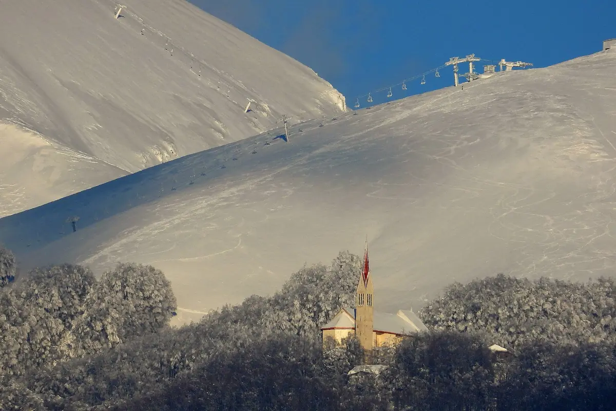 Pendii invernali del Terminillo con una chiesetta tra gli alberi brinati